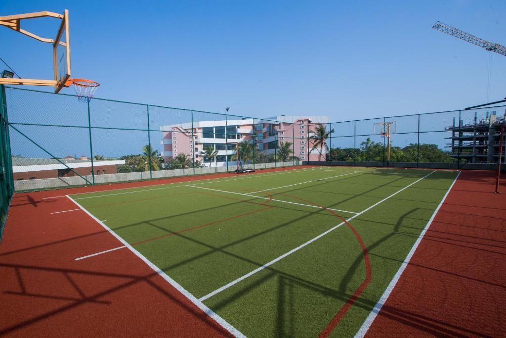 An outdoor basketball court with a net, surrounded by a fence.