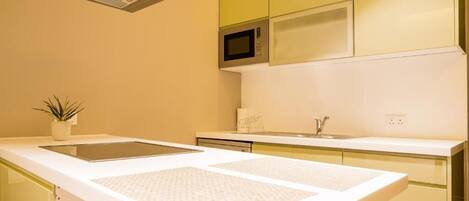 A modern kitchen with a microwave, a sink, and a countertop with a plant.