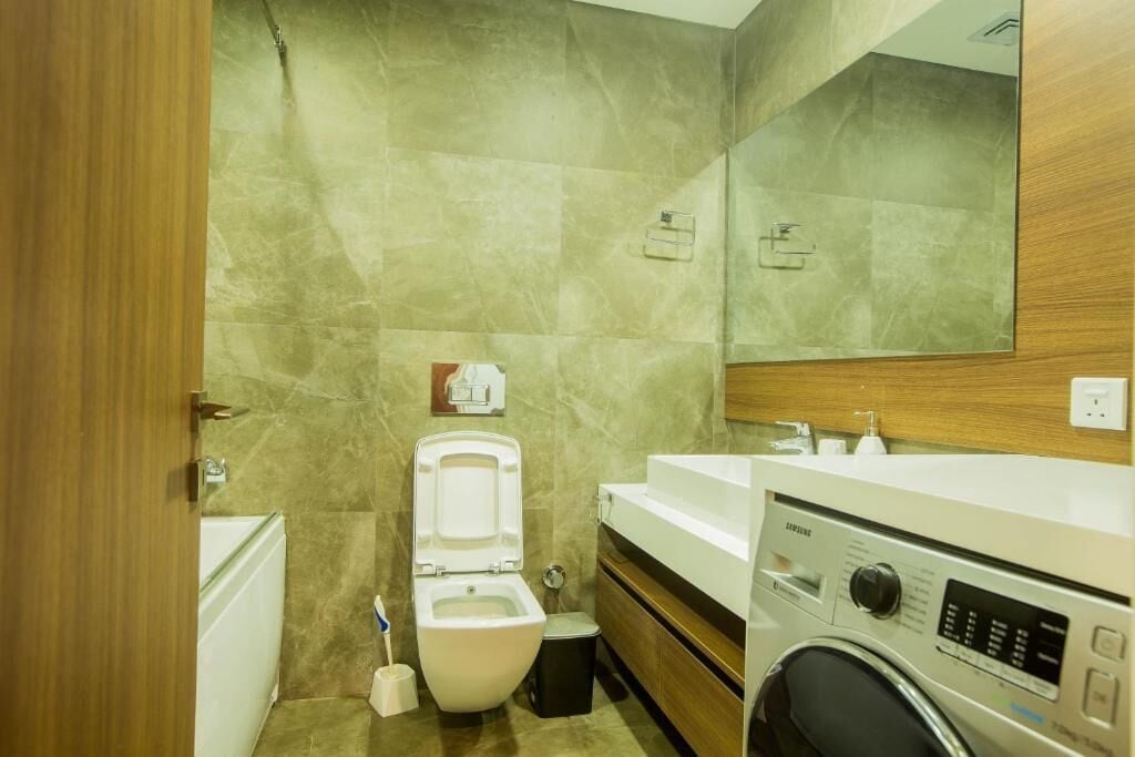 A bathroom with a toilet, sink, and washing machine.
