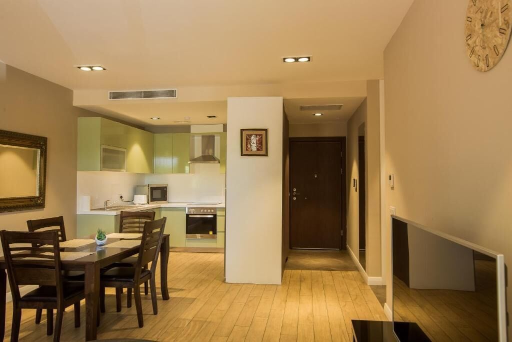 A modern kitchen with a dining area, a flat-screen TV, and a microwave.