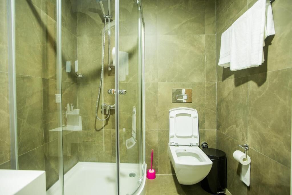 A modern bathroom with a glass-enclosed shower, a toilet, and a sink.