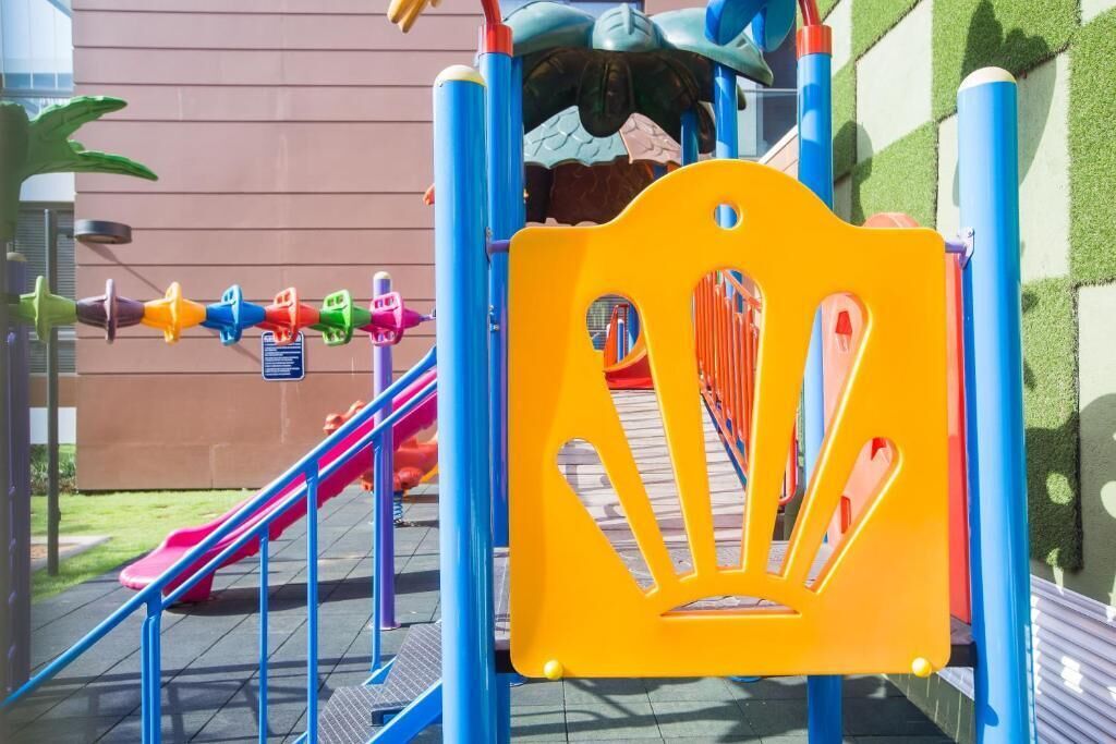 A playground with a slide, climbing structures, and a yellow safety guard.