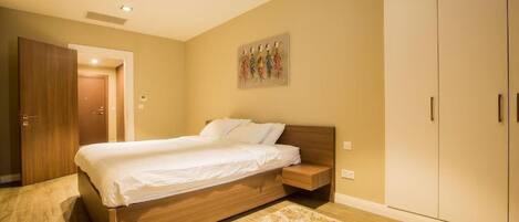 A bedroom with a wooden bed, a beige carpet, and a wardrobe.