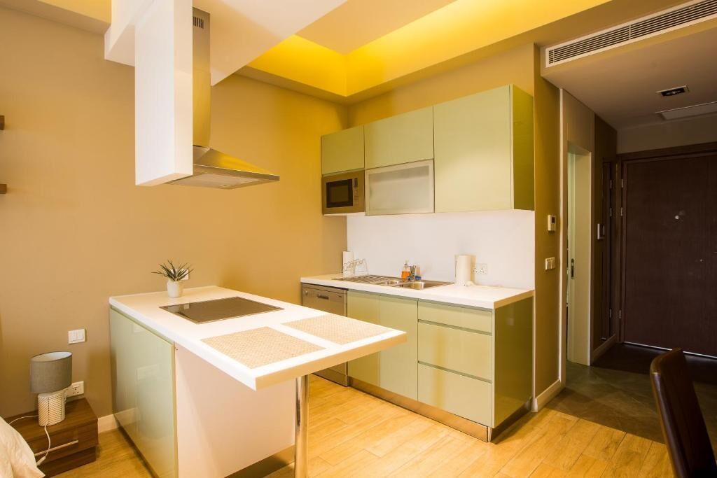 A compact kitchen with a microwave, sink, and a small island with a plant.