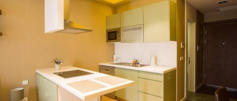 A compact kitchen with a microwave, sink, and a small island with a plant.