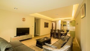 A modern living room with a sofa, TV, and dining area. - Accra Fine Suites  (Accra)