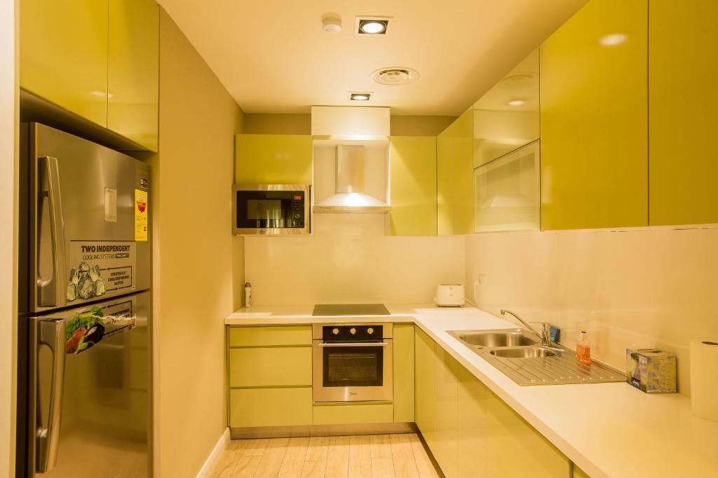 Una cocina compacta con un refrigerador de acero inoxidable, un horno empotrado y un microondas.