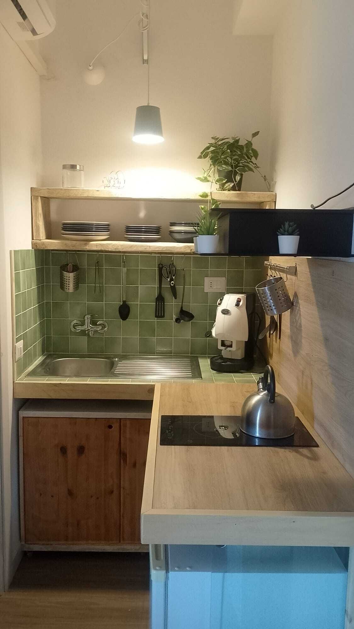 Eine kleine Küche mit Spüle, Wasserkocher und Arbeitsfläche.