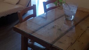 Un coin repas avec une table en bois, des chaises et une table avec un plateau en verre. Trois tableaux encadrés sont accrochés au mur au-dessus de la table.