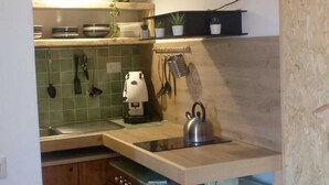 Une cuisine compacte équipée d’un évier, d’une bouilloire et de divers ustensiles.