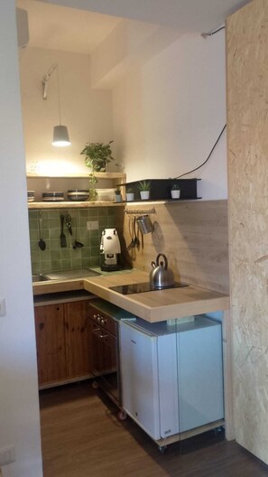 A compact kitchen with a sink, kettle, and various utensils.