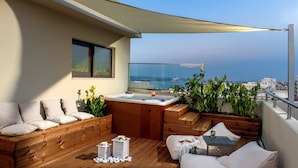 Una terraza en la azotea con piso de madera, bañera de hidromasaje y zonas de estar.