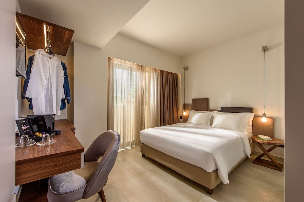 Een hotelkamer met een bed, bureau, stoel en spiegel.