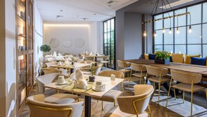 Un restaurante moderno con una larga mesa de comedor, múltiples sillas y un amplio ventanal con luz natural.