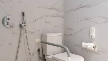 Um banheiro moderno com vaso sanitário, chuveiro com chuveiro manual e rolo de papel higiênico na parede.