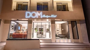 Un moderno hotel boutique con un letrero de neón, amplios ventanales y una entrada visible.