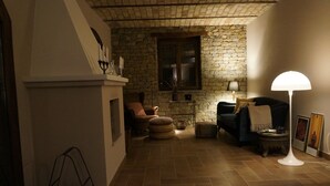 A cozy living room with a stone wall, a fireplace, a dark blue sofa, and a white floor lamp.