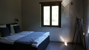 A bedroom with a bed, a window, and a tripod stand.