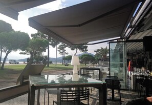 Un patio al aire libre con mesa y sillas de vidrio, una lámpara y vistas al parque y las montañas.