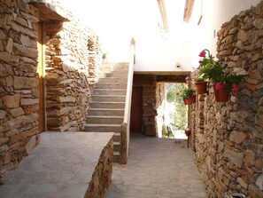 A stone staircase leading to a higher level, flanked by stone walls with hanging flower pots.
