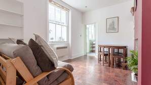 Un salon moderne avec un canapé en bois, une table à manger avec des chaises et une grande fenêtre.