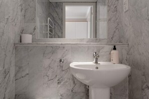 A bathroom with a marble sink and a mirror above it. - Bright, Modern One-bed With Stunning View of Thames (London)