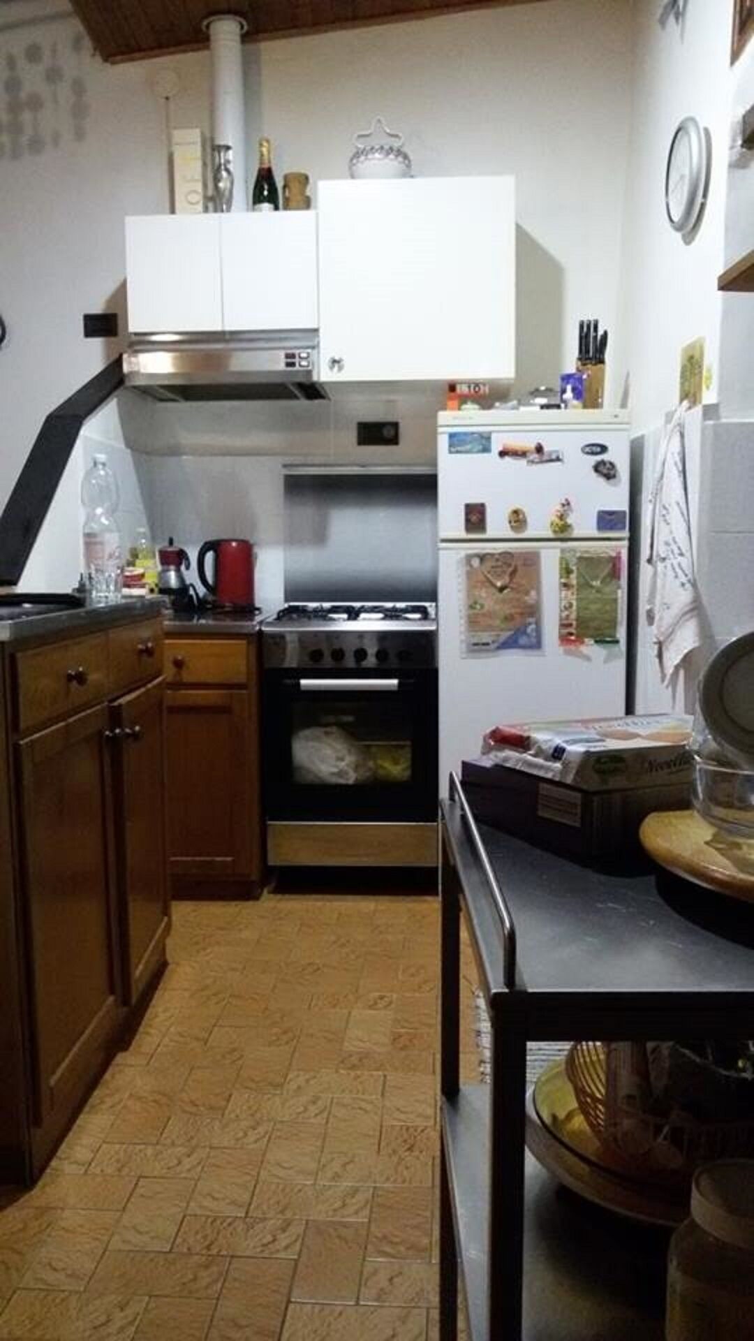 Una cucina compatta con piano cottura a gas, forno, mobili bianchi e frigorifero.