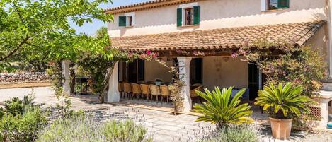 A Mediterranean-style villa with a tiled roof, outdoor seating area, and a garden with lavender plants.