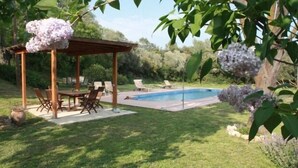 Eine überdachte Terrasse mit Pool, umgeben von üppiger Vegetation und blühenden Pflanzen.