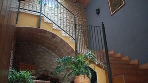 Eine Treppe mit Metallgeländer, einem steinernen Bogen und einem Blumentopf.