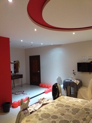 Ein Hotelzimmer mit einem Bett, einem Schreibtisch, einem Sessel und einem Fernseher an der Wand.