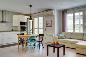 A modern kitchen with white cabinets, a dining table with chairs, a sofa, and a radiator. - Very cute apartment at only 5 Min Prince Felipe Pavilion (Zaragoza)