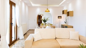 Un salon moderne avec un canapé beige, un coin repas doté d’une table en bois et une cuisine en arrière-plan.