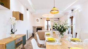 Un coin repas avec une table en bois dressée pour quatre personnes, des chaises blanches et des assiettes jaunes.