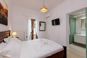 A hotel room with a bed, a TV, a bathroom with a mirror, and a window with curtains.