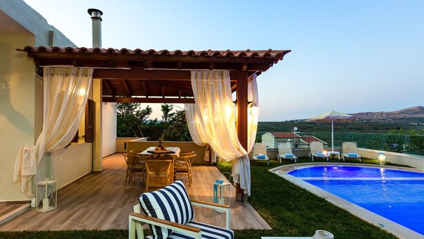 Un espace extérieur aménagé, abrité et doté d’une piscine, de mobilier en bois et offrant une vue sur le paysage.