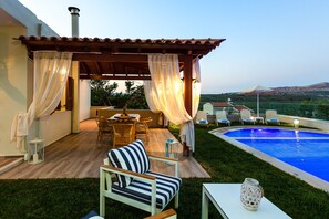 Un espacio de estar al aire libre cubierto con piscina, mobiliario de madera y vistas al paisaje.