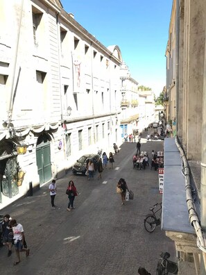 A cobblestone street lined with historic buildings, some with balconies and decorative elements.