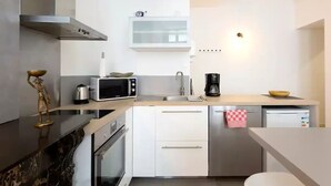 Una cucina moderna con mobili bianchi, un forno a microonde, una macchina da caffè e un lavello.