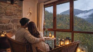 A couple sitting by a window overlooking a mountainous landscape, with wicker furniture and candles. - Rural apartment L'Arboleu de Traspeña for 2 people (Proaza)