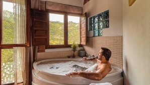 A man relaxing in a hot tub with a view of a mountainous landscape through a large window. - Rural apartment L'Arboleu de Traspeña for 2 people (Proaza)