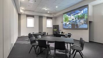 A modern conference room with a large screen displaying a building image, a projector, and a table with chairs.