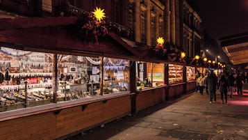 Una calle iluminada de noche con una hilera de tiendas exhibiendo diferentes productos.
