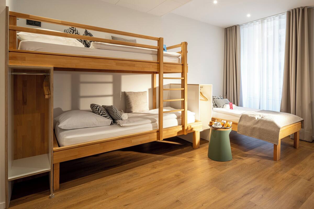A room with two bunk beds, a small table with a tray, and a window with curtains.