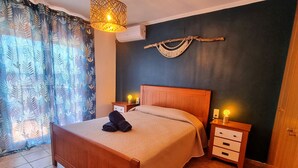 A neatly made bed with a folded towel, a wooden headboard, and a nightstand with a lamp. - Nice house for 8 people with private pool, wifi and 400m from the sea. (Ametlla de mar)