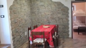 Ein Essbereich mit einer Steinsäule, einem Tisch mit roter Tischdecke und Holzsesseln.