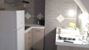 Eine kleine Küche mit Kühlschrank, Spüle und Arbeitsplatte.