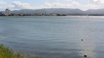 A calm lake with a distant shoreline featuring buildings and mountains.