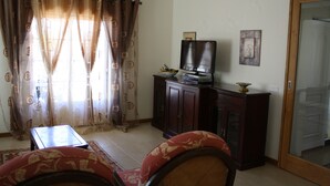 Una sala de estar con televisor, mueble de madera y sofá rojo.