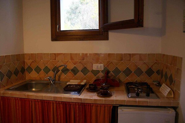 A kitchen with a sink, stove, and window above the counter. - L'aglientu - Olivo ROOM (Loiri Porto San Paolo)